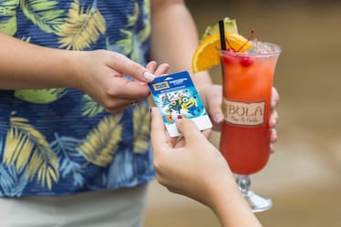A guest at Loews Royal Pacific Resort inside Universal Orlando hands her room key card to a server at Bula Bar & Grille in order to pay for the tropical drink she is about to receive.